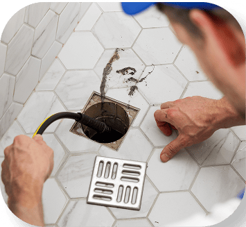 Plumber using a drain snake on a shower drain