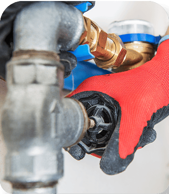 Gloved hands working on plumbing pipe with a wrench
